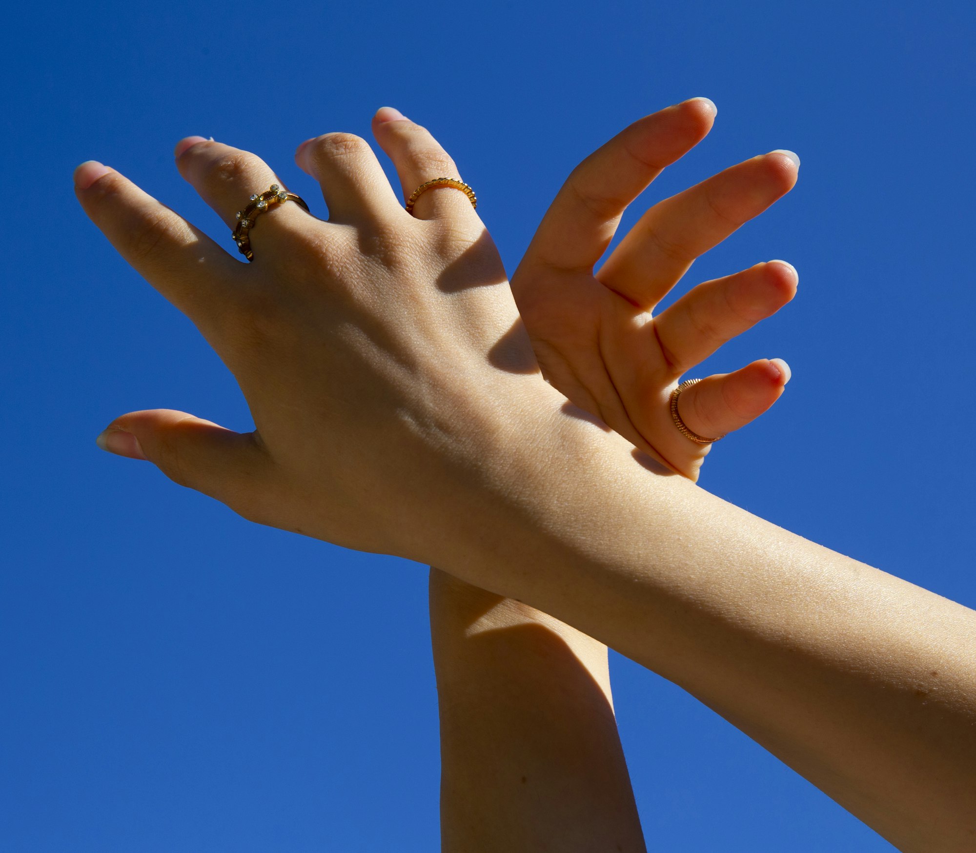 Hands with rings against a blue sky