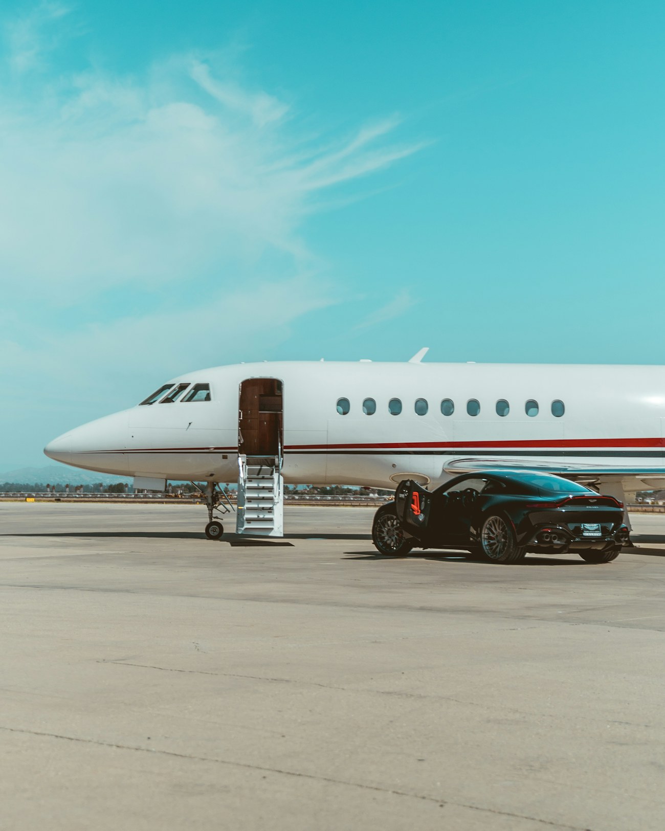 A private jet beside a supercar on the apron