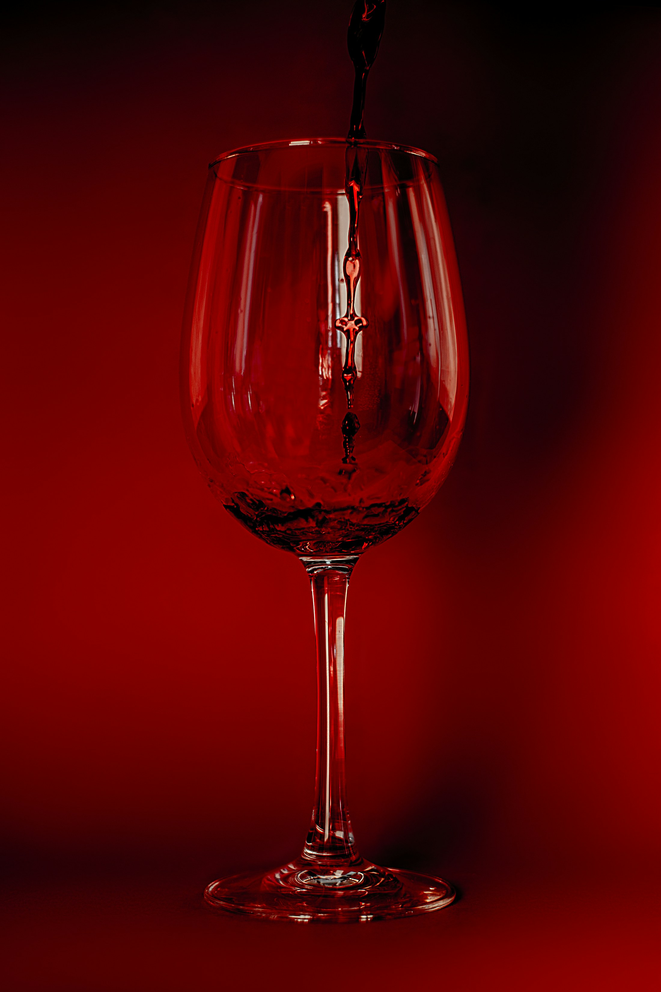 A glass of red wine on a red background