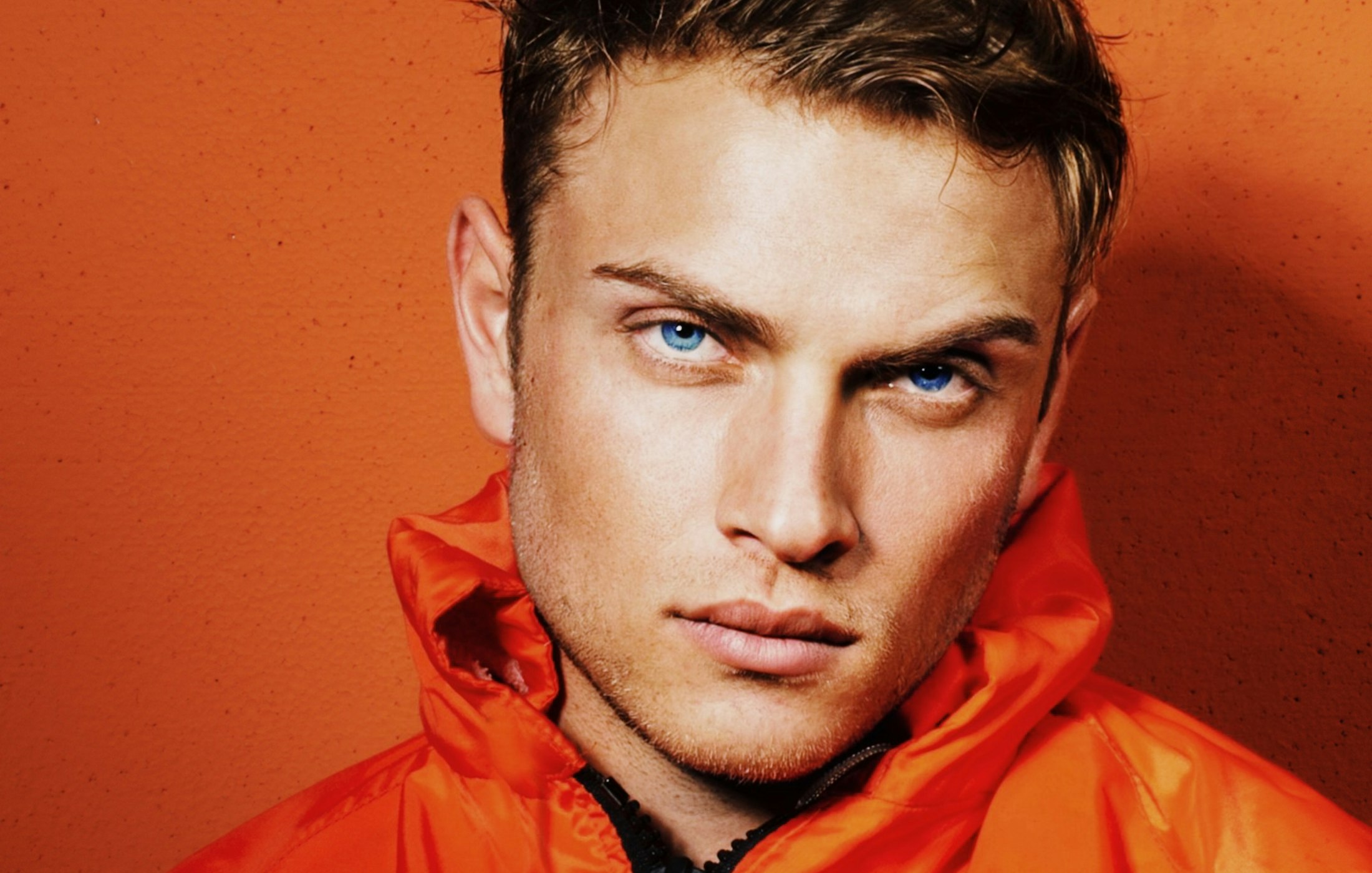 Male model in an orange jacket against an orange wall