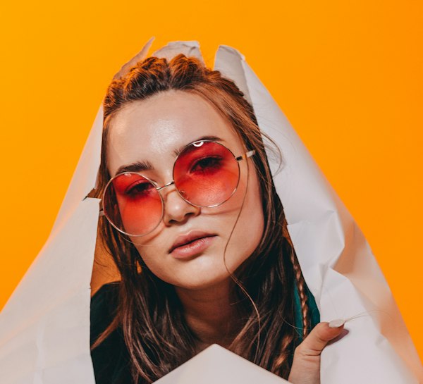 Model in pink sunglasses on an orange backdrop