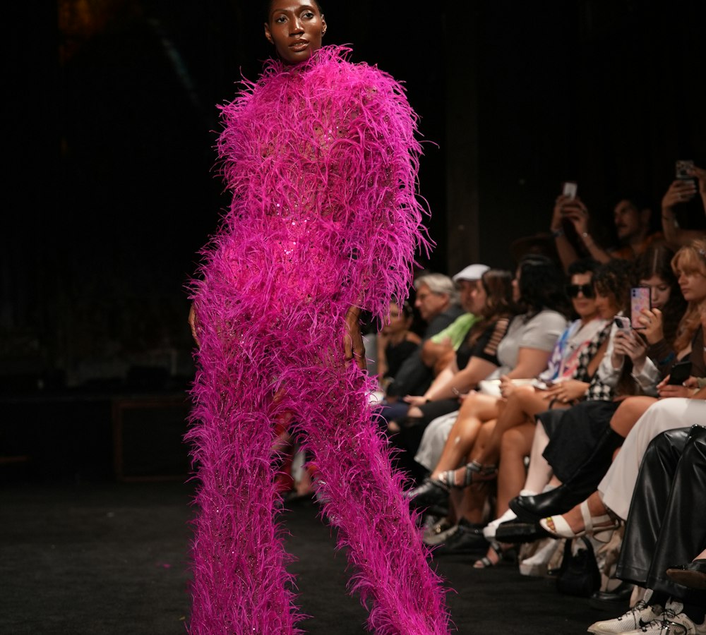 Model in a pink feathered suit on the runway