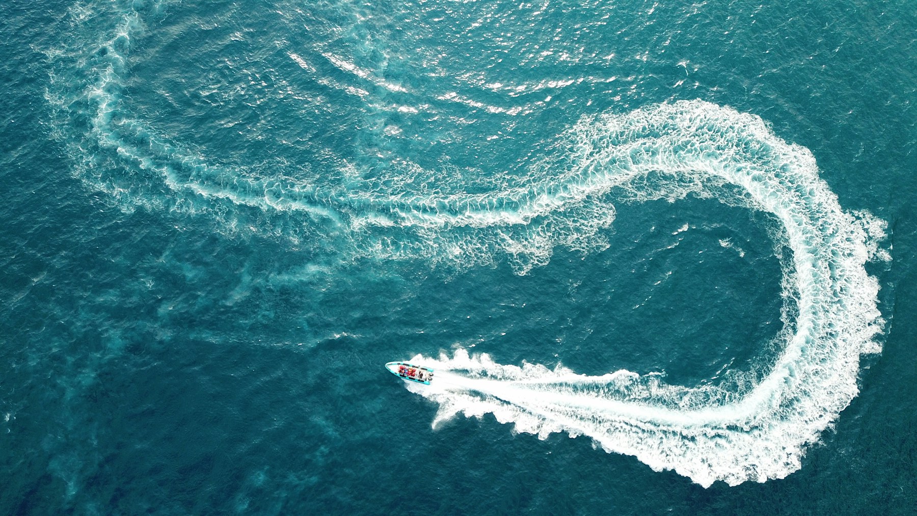 A yacht wake curving through turquoise water
