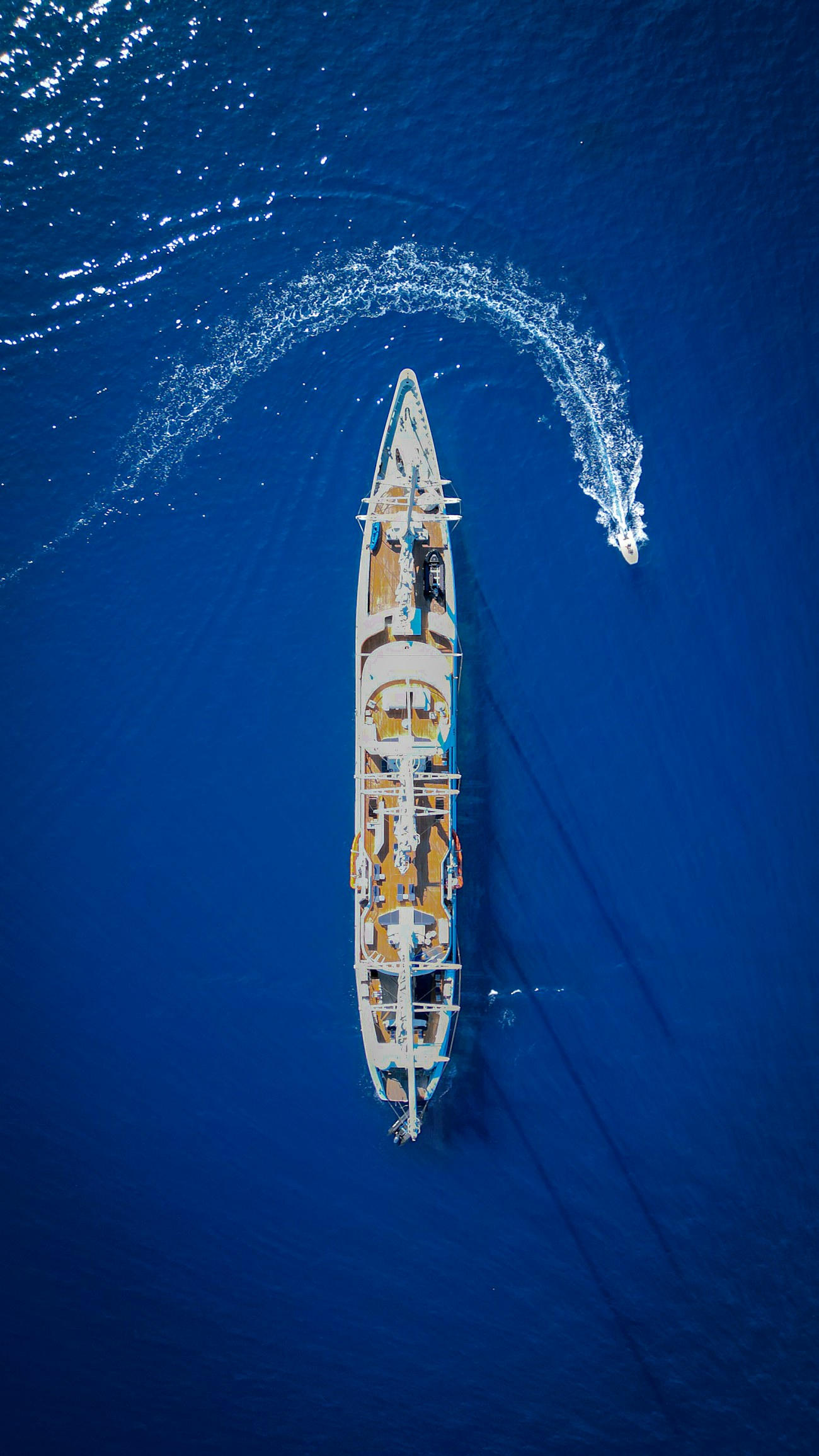 A yacht from above, wake curling behind