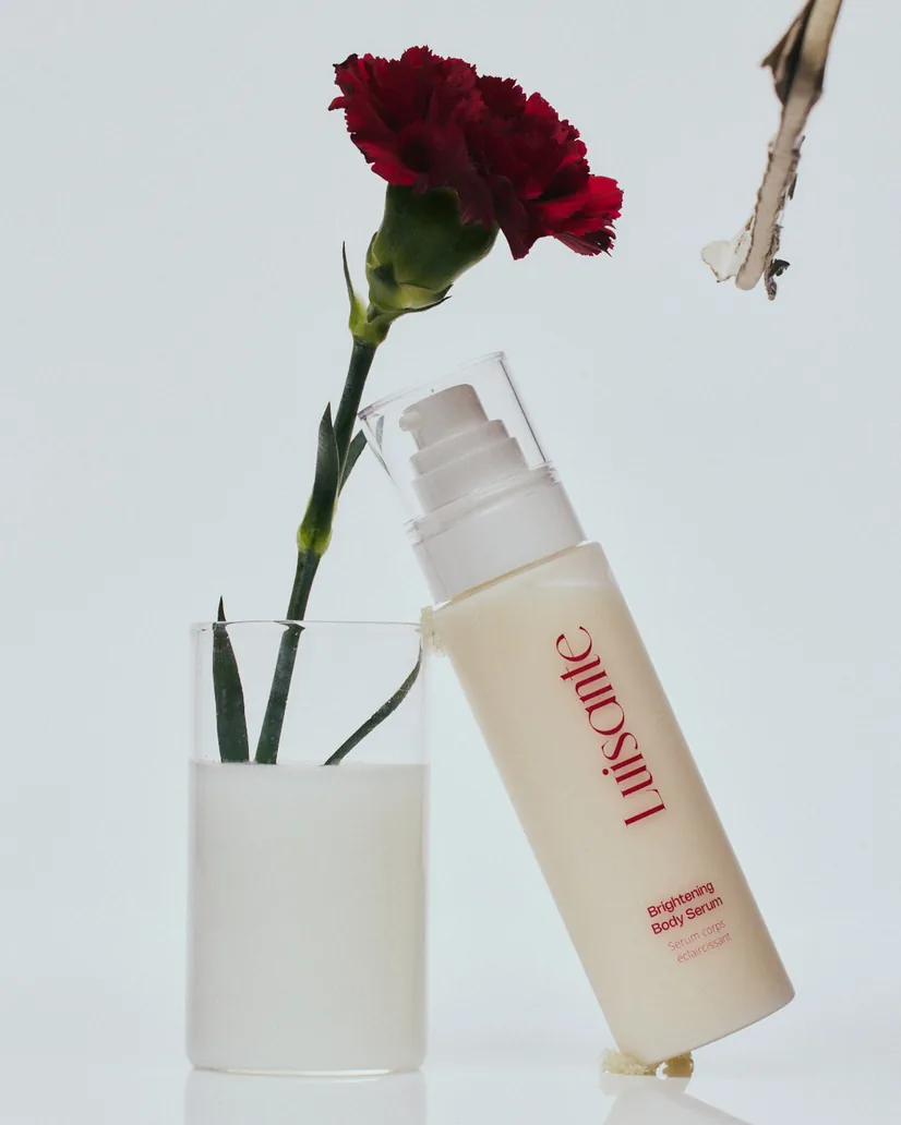 Brightening Body Serum beside a carnation