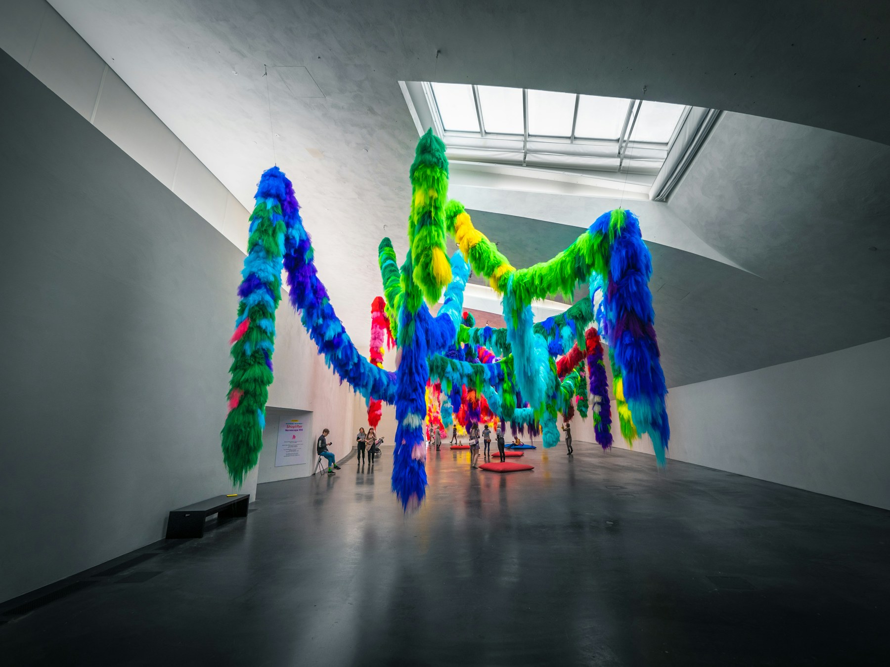 A colourful installation hanging in a white hall